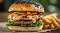 Juicy cheeseburger with melted cheese, crispy bacon, fresh lettuce on poppy seed bun served with golden french fries on kraft paper background.