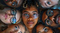 Diverse group of young adults with glasses forming a circle, looking up at camera with reflective lenses capturing light. Friendship concept.