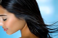 Young Hispanic woman with flowing dark hair against blue background, eyes closed in serene expression, showcasing healthy shiny hair movement for beauty and haircare advertising.