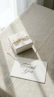 Elegant white gift box with ribbon bow and thank you card on linen surface in soft natural light, perfect for gratitude and celebration concepts.