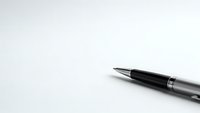 Black ballpoint pen with silver accents on clean white paper background for business writing and office documentation needs.