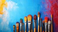 Artist paintbrushes arranged in row on vibrant multicolored textured background with blue sky gradient and red abstract paint strokes, creative art supplies.