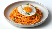 Delicious spaghetti pasta with tomato sauce topped with fried egg and fresh herbs served on white plate for breakfast or dinner meal preparation.