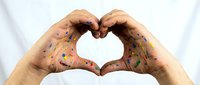 Hands covered in colorful paint forming a heart shape against a white background, symbolizing creativity, love of art, and artistic passion.