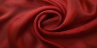 Luxurious deep red silk fabric forming elegant swirl pattern with soft folds and curves, creating dramatic light and shadow effect. Suitable for fashion and luxury backgrounds.