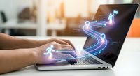 Hands typing on laptop with glowing digital roadmap, route icons and goal flag rising from screen, symbolizing business strategy and planning.
