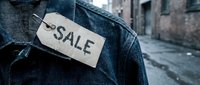 Denim jacket with a rustic cardboard sale tag pinned to the chest, urban alley background, moody atmosphere for retail and fashion concepts.