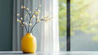 Yellow ceramic vase with delicate white flowers on windowsill against soft natural daylight and blurred green background creates minimalist home decor composition.