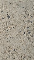 Close-up of sandy beach surface with scattered dark pebbles and shells, suitable for backgrounds, textures, and coastal design projects.