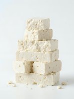 Stacked blocks of creamy white cheese with crumbly texture isolated on white background, ready for food and culinary design projects.