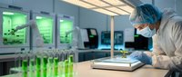 Laboratory scientist in protective gear conducting research with green samples in modern scientific facility for biotechnology development.