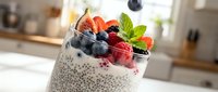Chia seed pudding topped with fresh berries, strawberries, and mint leaves in a glass on kitchen counter. Healthy breakfast or dessert.