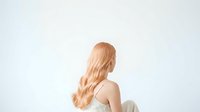 Woman with long, wavy blonde hair styled in loose waves, shown from behind against a white background. Isolated stock photo suitable for hair care, beauty, and wellness design projects.