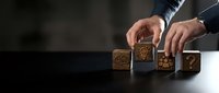 Business professional arranging wooden blocks with innovation icons on dark surface representing strategic planning and creative problem-solving concepts.