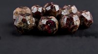 Raw garnet gemstones with natural crystalline formations on dark surface for jewelry making and mineral collection purposes.