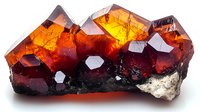 Glowing orange-red garnet crystals cluster formation on white matrix showing natural geometric shapes and translucent properties in mineralogy specimen.