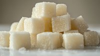 White sugar cubes stacked in pyramid formation with crystalline texture and soft focus background, macro photography highlighting sweetness and culinary elements.