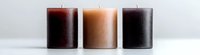 Three minimalist pillar candles in brown, beige and black colors arranged in row on white background, creating modern home decor composition with clean aesthetic appeal.