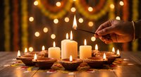Hand lighting candles with match during festive celebration with warm bokeh lights creating cozy atmospheric ambiance for holiday decorating and seasonal traditions.