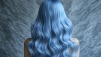 Young woman with long wavy pastel blue hair shown from behind against gray textured background, demonstrating professional hair coloring and styling technique.
