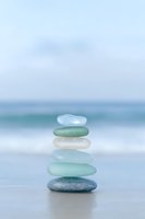 Zen stone stack balanced on beach with ocean waves creating peaceful meditation and mindfulness concept for wellness and spiritual harmony.
