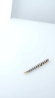 Elegant silver ballpoint pen with gold accents on clean white surface for business writing and professional correspondence.