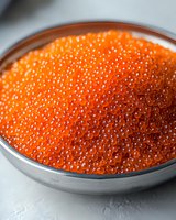 Fresh red caviar in metal bowl on light background, macro shot showing detailed texture of salmon roe pearls for gourmet food and restaurant menu design.