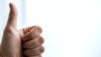 Male hand showing thumbs up gesture against white background expressing approval, success and positive feedback for business presentations.