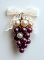 Elegant grape cluster made of burgundy and pearl beads with delicate white lace bow on neutral background for craft and jewelry making projects.