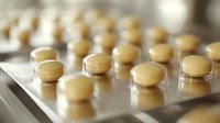 Yellow round pills in blister pack on light background, macro shot with selective focus showing pharmaceutical medicine and healthcare concept.