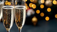 Sparkling champagne flutes with bubbles against blurred golden bokeh lights background, festive celebration atmosphere for holiday events and parties.