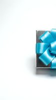 Elegant gift box with turquoise satin ribbon bow on white background for celebrations, holidays and special occasions.