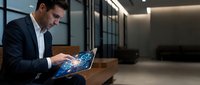 Middle-aged male professional in dark business suit and white shirt working on glowing laptop with digital network interface in modern office lobby with wooden bench and contemporary lighting.