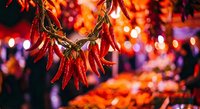 Red chili peppers hanging in bunches with warm bokeh lights creating festive atmosphere for culinary and harvest celebrations.