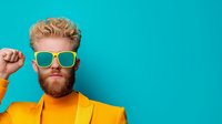 Young bearded man in yellow turtleneck and mint sunglasses posing confidently against turquoise background, expressing positive attitude and modern style.