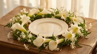 Elegant floral wreath with white calla lilies and small blooms surrounding a ceramic plate on a wooden table, perfect for wedding or event decor.