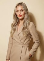Young blonde businesswoman in beige coat portrait against neutral background for professional corporate fashion and workplace style concepts.