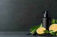 Black cosmetic bottle with fresh citrus fruits and green leaves on dark background. Natural skincare concept with copy space for product placement.