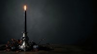 Lit black candle in ornate silver candlestick surrounded by dried branches and autumn foliage against dark moody background for Halloween, gothic, or memorial design projects.