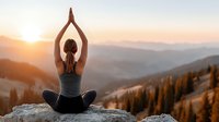 Woman practicing yoga meditation pose on mountain peak during golden sunrise with peaceful valley landscape below for wellness and mindfulness concepts.