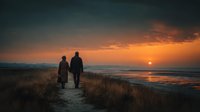 Two people walking on coastal path during golden sunset over ocean with dramatic sky and warm light reflecting on water creating romantic peaceful atmosphere.