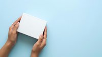 Hands holding blank white box on light blue background, overhead view for product packaging mockup and branding presentation.