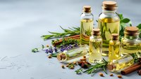 Essential oils in glass bottles with cork stoppers surrounded by fresh herbs, spices and aromatic plants for natural wellness and aromatherapy treatments.