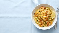 Shrimp scampi pasta with garlic, lemon, and herbs served on white plate, overhead view for restaurant menus and food blogs.