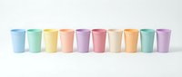 Row of pastel colored plastic cups in rainbow gradient arrangement isolated on white background, perfect for party, kitchen, and lifestyle product concepts.