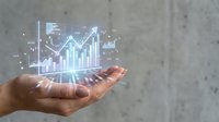 Businessman hand holding glowing digital financial charts and upward trending graphs, representing growth, analytics, and investment success in modern business.