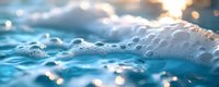 Close-up of ocean waves with white foam and bubbles, bright sunlight reflecting off water surface, suitable for travel, nature, and wellness backgrounds.