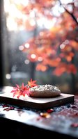 Chocolate glazed donut on wooden board with autumn maple leaves and bokeh light background, moody fall season food photography composition.