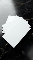 Stack of blank white paper sheets on black marble surface for business stationery mockup and branding presentation projects.