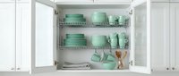 Organized kitchen cabinet with mint green dinnerware set, plates, bowls and accessories on wire shelving for home storage and organization solutions.